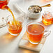 A glass cup of Davidson's Organic Peach Apricot Essence Tea being poured.