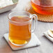 A glass mug of brown Davidson's Organic Coconut Chai tea on a white marble coaster.