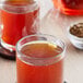 A glass of brown Davidson's Organic Tulsi Rooibos Chai tea with a tea bag on top.