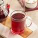 A glass mug of Davidson's Organic Spring Fruit and Flowers red tea on a cutting board.