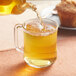 A person pouring Davidson's Organic Lemon Medley Herbal Loose Leaf Tea into a glass cup.