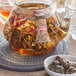 A glass teapot with Davidson's Organic Spring Cup Tea Blooms in liquid.