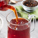 Davidson's Organic Spiced Raspberry Loose Leaf tea being poured into a glass cup.