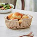 An Acopa gold wire basket filled with bread rolls.