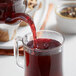 A teapot pouring Davidson's Organic Seasons Herbal tea into a glass cup.