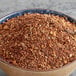 A bowl of brown and red spices on a table.