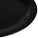 A close-up of a Carlisle black melamine plate with a curved edge.