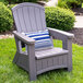 A Suncast gray resin Adirondack chair with a blue and white striped pillow sitting in the grass.