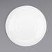 A white Corona by GET Enterprises porcelain plate with a round rim on a gray surface.