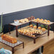 An Abert copper buffet podium on a table with trays of pastries and cakes.