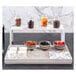 A dark gray Abert Domino tile display with bowls of fruit and jars of yogurt on a hotel buffet table.