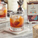 A glass of Runamok Maple Old Fashioned Cocktail Syrup with ice and orange slices.