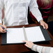 A person holding a pen over a Menu Solutions reservation binder.