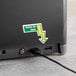 A black Powers Paper interfold napkin dispenser on a table with a power cord and a green arrow.