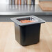 A black container with a Cambro 1/6 size clear plastic lid on a counter with carrots inside.