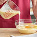 A person pouring sweetened condensed milk into a bowl of food.