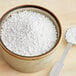 A bowl of white powder next to a spoon.