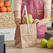 A woman holding a pear in a Choice brown paper bag.