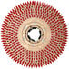 A close-up of a white circular tufted pad driver with red tufts.
