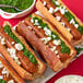 A plate of Tofurky vegan kielbasa hot dogs with green pesto and onions.