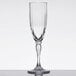 A clear GET SAN plastic champagne flute with a fluted design and a stem on a table.