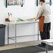 A man in a chef's uniform preparing food on a Regency stainless steel work table.