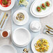 A white table with white stackable porcelain cups on white plates.