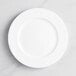 An Acopa Cordelia porcelain plate with a wide, rippled edge and a circular pattern on a white surface.