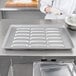 A person in a kitchen using a Chicago Metallic hot dog bun pan to bake.