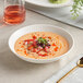 A bowl of soup with strawberries and sprouts in an Acopa Cordelia coupe bowl with a spoon on a napkin.