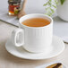 An Acopa Cordelia bright white porcelain cup of tea on a saucer.