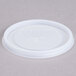 A white plastic Cambro lid with a straw slot and cross on it.