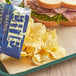 A tray with a sandwich and a bag of Kettle Brand Sea Salt & Vinegar Potato Chips.