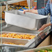 A woman holding a Choice full size aluminum steam table water pan.