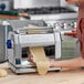 A woman using an Imperia electric pasta machine to roll out dough.