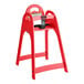 A red assembled high chair with a safety strap and a handle cutout on the backrest.