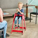 A red designer high chair for children, shown assembled and in use at a restaurant table.