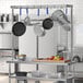 A kitchen with pots and pans hanging from a Regency stainless steel table-mounted pot rack.