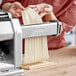 A woman using an Imperia pasta machine to make Reginette pasta.