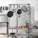 A stainless steel kitchen with pots and pans hanging from a Regency table-mounted pot rack.