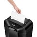 A hand putting paper into a Fellowes paper shredder.