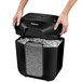 A person holding a black Fellowes Powershred LX25 paper shredder with a transparent lid.