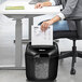 A woman sitting at a desk using a Fellowes Powershred LX25 paper shredder.