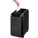 A person's hand putting a piece of paper into a Fellowes Powershred LX220 black shredder.