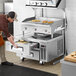 A man using a Cooking Performance Group countertop electric griddle to cook food.