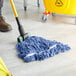 A person cleaning a hospital cafeteria floor with a Lavex Blue Cotton Blend Wet Mop.
