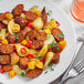 A plate of food with Field Roast Spicy Mexican Chipotle sausage links and potatoes with a fork and knife.