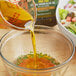 A bowl of salad with Colavita Extra Virgin Olive Oil being poured into it.