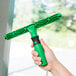 A hand holding a green and black Unger ErgoTec T-Bar window cleaner.