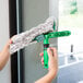 A person using an Unger ErgoTec T-Bar StripWasher Handle to clean a window.